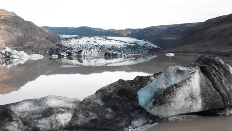 Dirty-icebergs-in-muddy-Solheimajokull-glacier-moraine-lake,-Iceland