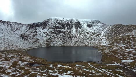 Aerial-drone-video-of-Red-Tarn-and-Helvellyn-in-the-snow---Lake-District,-UK