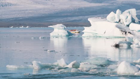 Cruise-boat-with-tourists-sailing-in-arctic-sea-with-icebergs,-Iceland