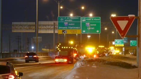 Plowing-trucks-cleaning-a-highway,-after-a-snow-storm,-at-night,-with-yellow-lights-on