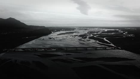 Aerial-flying:-bridge-leading-over-glacial-river-bed-in-iceland-landscape-view