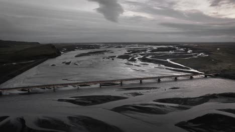 Aerial-orbit:-bridge-leading-over-glacial-river-bed-in-iceland-landscape-view