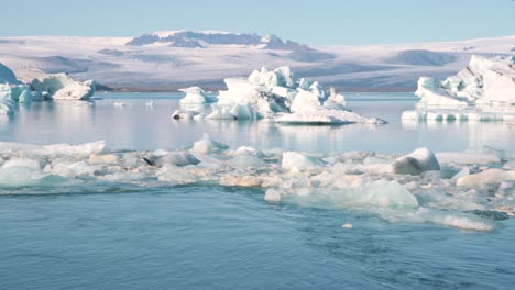 Icebergs-and-ice-floes-in-arctic-sea-lagoon-in-mountainous-landscape