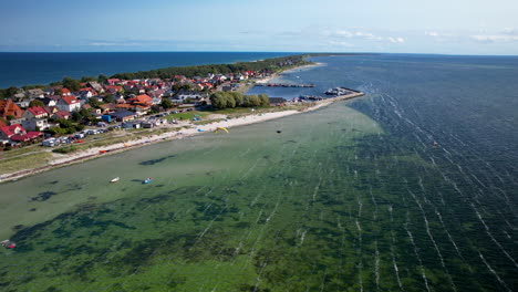 High-angle-shot-of-a-seaside-town-with-houses,-beach,-and-shallow-green-waters