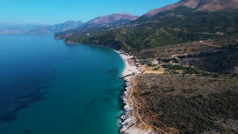 Azure-Deep-Sea,-Rocky-Shore,-and-Green-Olive-Hills-Create-a-Picturesque-Canvas-at-the-Idyllic-Lukova-Beach-in-Albania