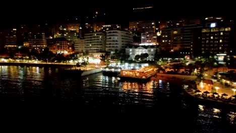 Magia-Nocturna-En-Saranda:-Barcos-Anclados,-Luces-Iluminadas-En-El-Muelle-Y-Un-Animado-Paseo-Marítimo-Pintan-Una-Imagen-Impresionante-Del-Turismo-Costero