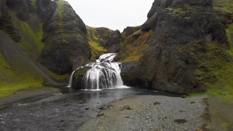 Cascading-Stjornarfoss-waterfall-flowing-over-rocks-in-mossy-gorge