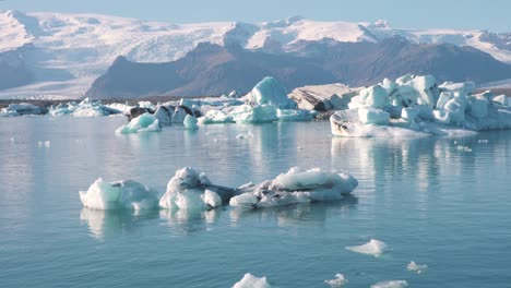 Laguna-De-Mar-Frío-En-El-Océano-ártico-Con-Icebergs-Y-Montañas-Más-Allá