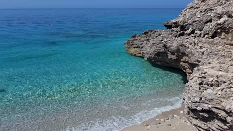 Día-Brillante-En-Una-Playa-Tranquila,-Aguas-Azules-Bañando-Suavemente-Las-Rocas,-Creando-Un-Sereno-Refugio-Costero-En-Albania