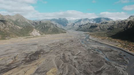 Aerial-thorsmörk-glacial-river-bed-in-mountain-ranges,-sunny-day-famous-icelandic-national-park-landmark-landscape
