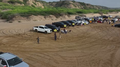 Drohne-Fliegt-über-SUV-Jeep-Fahrzeug-Rallye-Parkplatz-Im-Sand-In-Der-Nähe-Des-Strandes