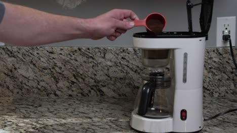 A-man-puts-a-filter-in-a-coffee-maker-and-fills-it-with-coffee-grinds