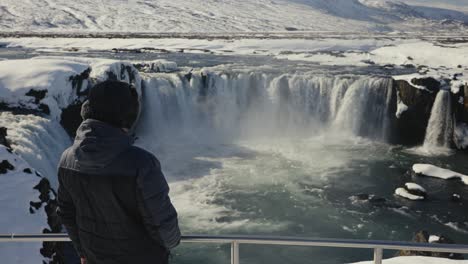 Man-come-closer-to-metal-safety-barrier-at-Godafoss-waterfall-sightseeing-area