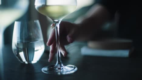 Person-placing-glass-of-wine-down-on-table-of-fine-dining-restaurant,-close-up