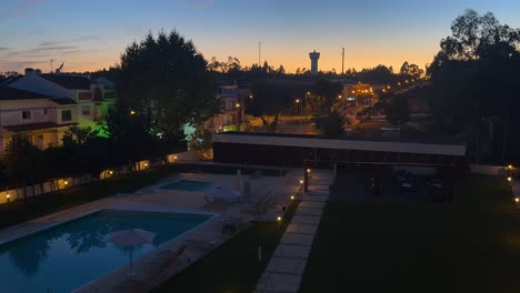 Timelapse-of-the-city-of-Lisbon-at-dusk-with-a-swimming-pool-in-the-foreground,-Portugal