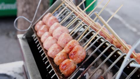 Small-sausages-skewed-in-twos-grilled-on-charcoal-as-common-Street-Food-along-Sukhumvit-Road-in-Bangkok,-Thailand