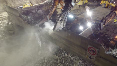 Row-of-excavators-with-shear-tools-demolish-concrete-bridge-during-nighttime