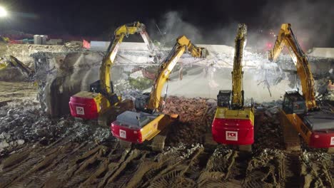 Excavators-break-down-dam-at-night-using-bright-lights-to-illuminate-work-site