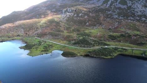 Wide-rotating-drone-shot-of-Gap-of-Dunloe,-Bearna-or-Choimín,-mountain-pass-in-County-Kerry,-Ireland-with-the-lake-shoreline