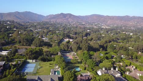 Drone-shot-of-Mansions-in-Malibu,-California-with-Santa-Monica-Mountains-and-Pacific-Ocean-in-Background-on-Sunny-day
