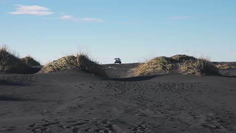 Car-parked-between-two-grass-turfs-on-black-sand-beach-in-Iceland