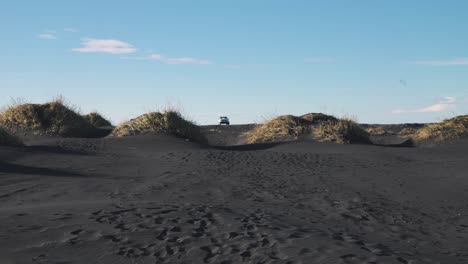 Car-parked-between-black-sand-beach-dunes,-other-drives-away,-Iceland