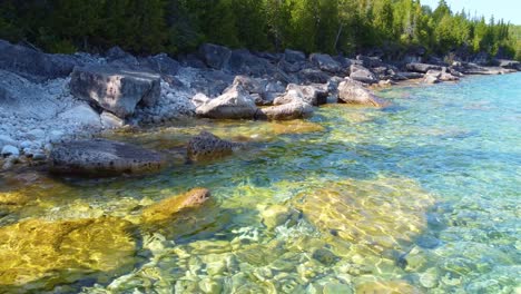 Flying-low-over-rocks-and-crystal-clear-waters-in-Georgian-Bay,-Ontario
