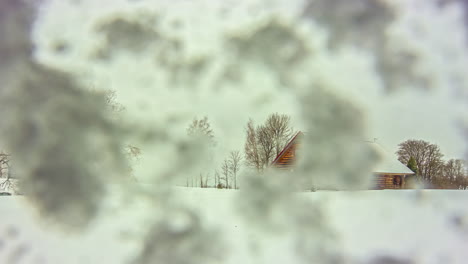 Timelapse-shot-of-a-wooden-cabin-in-the-middle-of-snowfall-with-camera-covered-with-snow-on-a-cold-winter-day