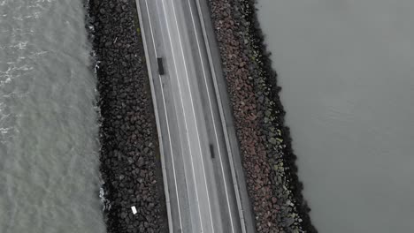 Antena-De-Una-Carretera-Vacía-Y-Un-Puente-Rodeado-Por-El-Mar-En-Islandia