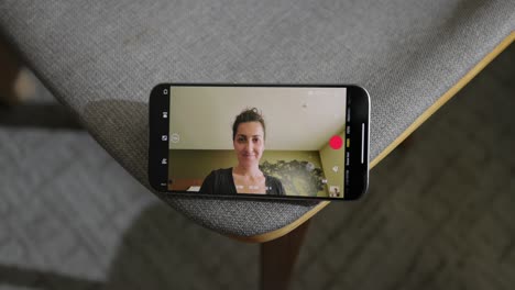 Talking-To-Female-Friend-Via-Videocall-On-Smartphone-Whilst-Tapping-Icons-On-Screen