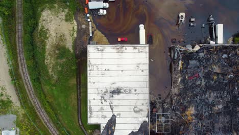 Aerial-top-view-over-a-burnt-industrial-business,-extinguished-fire-of-hazardous-materials,-oil-pollution