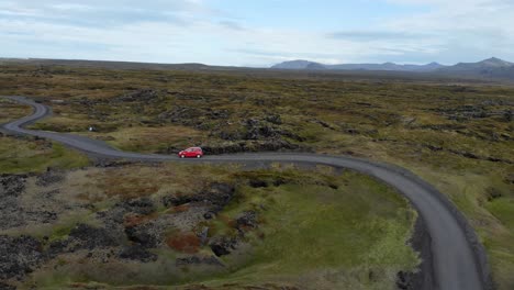 Luftaufnahme-Eines-Kleinen-Roten-Autos-Auf-Einer-Kurvenreichen-Straße-In-Der-Isländischen-Landschaft
