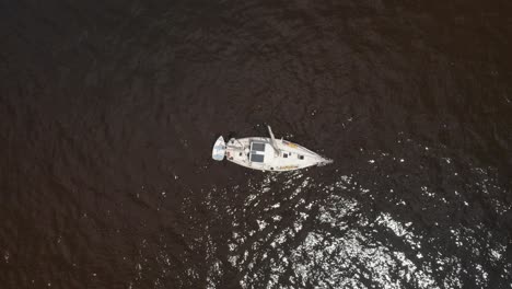 Aerial-bird's-eye-drone-shot-overlooking-the-water-marina-in-water-sailboat-vessel-fisherman
