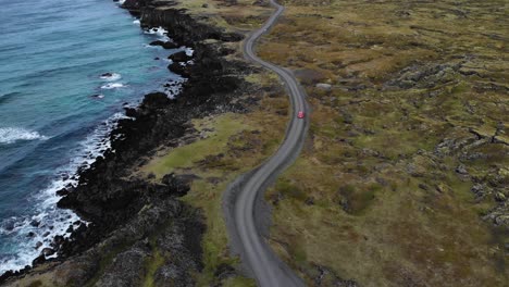 Luftaufnahme-Eines-Roten-Autos,-Das-Auf-Einer-Kurvenreichen-Straße-An-Der-Küste-Islands-Fährt