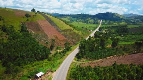 Vehículos-Que-Viajan-Por-Una-Carretera-Rural-A-Través-De-Pintorescas-Montañas-En-Uganda---Toma-Aérea-De-Drones