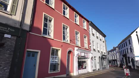 Walking-on-the-street-with-bookshop-and-cafes-in-Kinsale,-county-Cork-in-Ireland
