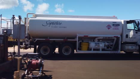 Gimbal-wide-shot-from-a-moving-vehicle-dollying-past-a-helicopter-getting-refueled-from-a-gas-truck-at-a-heliport-in-Kaua'i,-Hawai'i