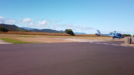 Gimbal-wide-shot-from-a-moving-vehicle-dollying-past-various-helicopters-from-aerial-tour-companies-lined-up-on-the-tarmac-at-a-heliport-in-Kaua'i,-Hawai'i