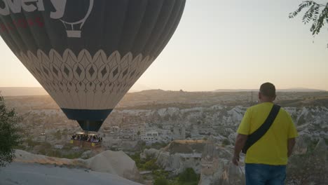 Man-observes-tourists-hot-air-balloon-slowly-descend-Goreme-valley