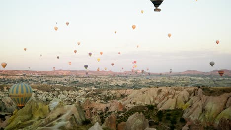 Hot-air-balloons-fill-sky-Rose-valley-Cappadocia-rocky-landscape