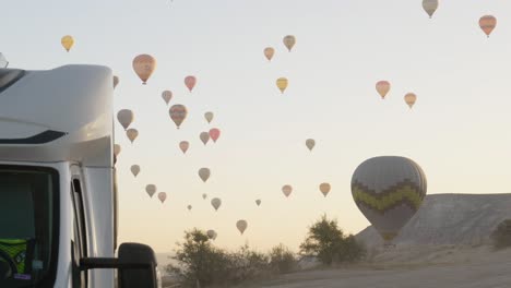 Early-morning-hot-air-balloons-flight-over-motor-home-tourism-concept
