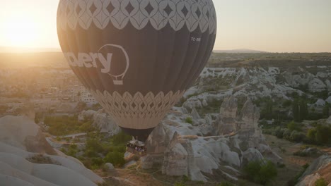 Hot-air-balloon-passengers-descend-into-rocky-valley-landscape-sunrise