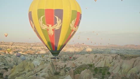 Colourful-hot-air-balloon-floats-over-red-valley-rocky-landscape