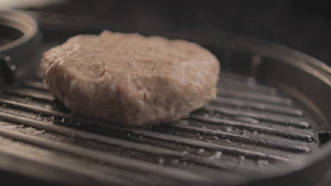 Roher-Rindfleisch--Oder-Hähnchenburger-Auf-Dem-Grill,-Der-Für-Ein-Köstliches-Burger-Sandwich-Zubereitet-Wird,-Mit-Schwarzem-Hintergrund-Und-Einfachem-Lichtaufbau,-Aufgenommen-Auf-Rohem-4k