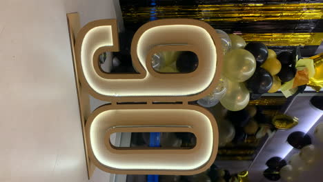 90th-anniversary-cardboard-symbol-with-LED-lights-with-black-and-gold-decoration-in-the-background