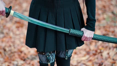 Young-girl-in-a-black-skirt-with-garters-and-stockings-pulls-out-a-katana-sword