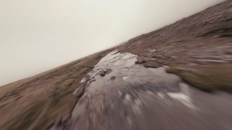 FPV-Luftaufnahme-Eines-Baches-Und-Wasserfalls-Auf-Einer-Isländischen-Wiese