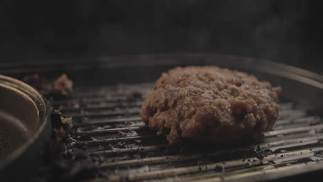 Raw-Beef-or-Chicken-Burger-on-grill-being-prepared-for-a-delicious-burger-sandiwich-and-flipped-,-with-a-black-background-and-simple-light-set-up-shot-on-RAW-4K