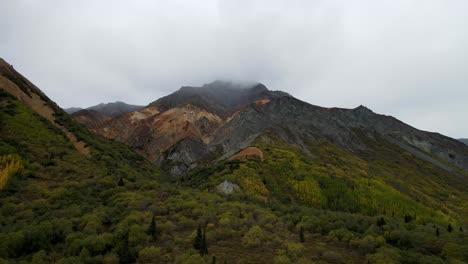 Montaña-Colorida-Con-Una-Capa-De-Nubes-Rodeada-De-Pinos-Y-Arbustos-Verdes-En-Alaska