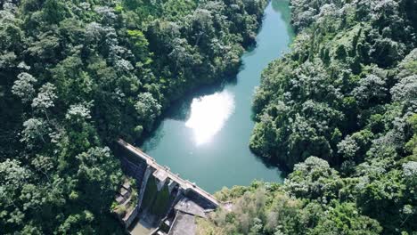 Aerial-top-down-shot-of-Tireo-Dam-with-green-river-and-green-nature-during-sunny-day-in-Bonao,-Dominican-Republic